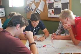 Photograph of a group of young students writing on a large sheet of paper during a "Silent Discussion on Ethical Dilemmas" class